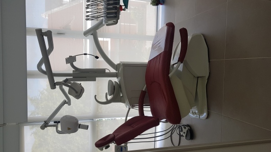 Modern bright dental clinic interior with an ergonomic sleek white and teal dental chair, high-tech dental examination equipment, clean clinical lighting, wooden and teal accents, minimalist aesthetic, professional photography, warm welcoming medical office in Buenos Aires, sharp focus, 8k